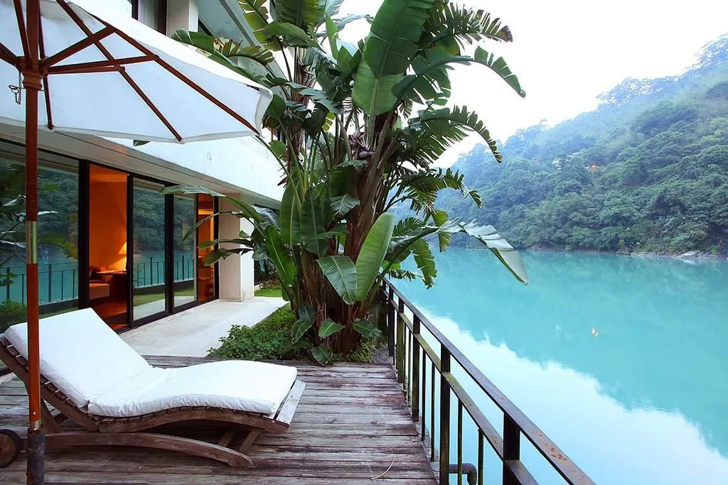 white lawn chair under umbrella on deck in front of river