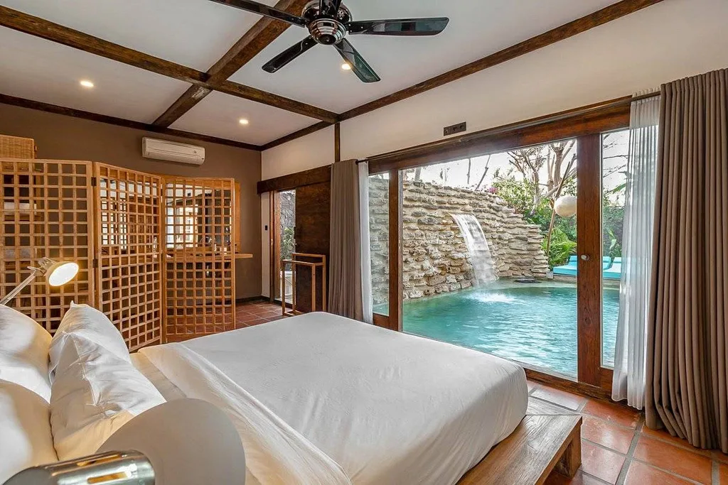 resort room with bed in front of private pool