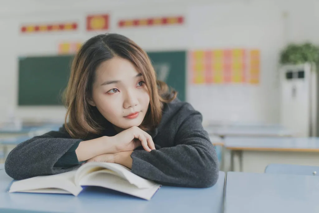 young Asian woman sitting at table thinking