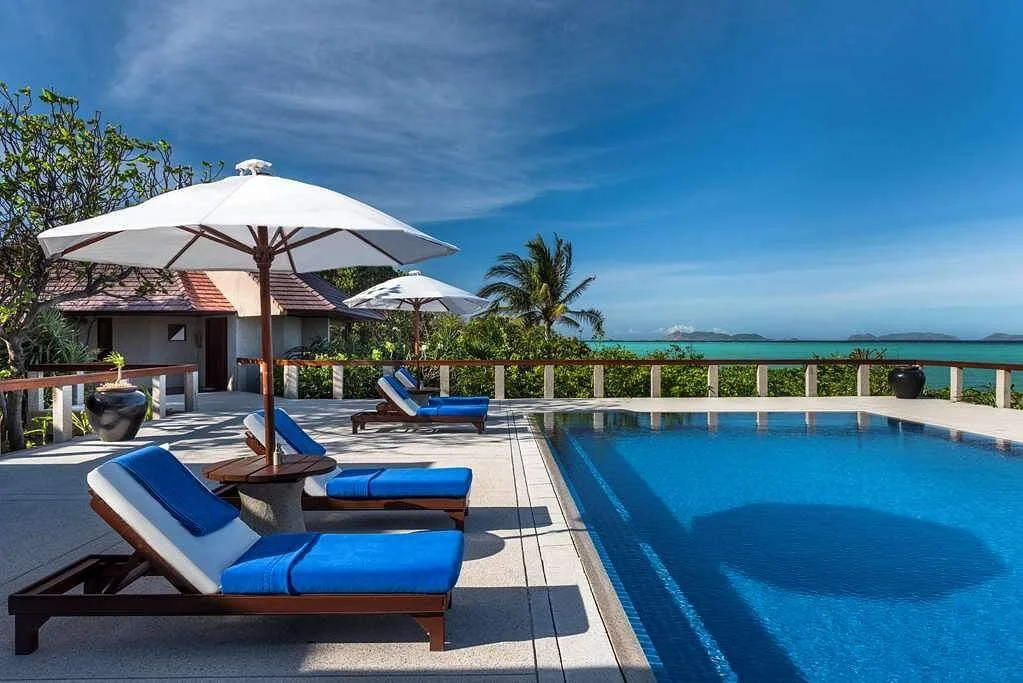 two lawn chairs next to square resort pool