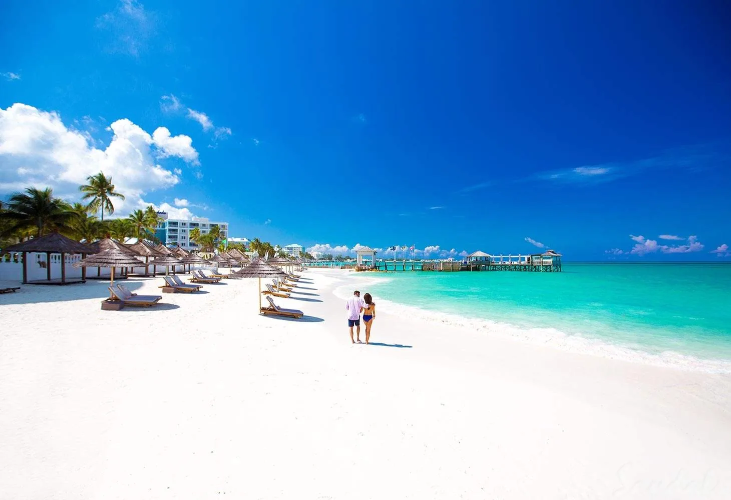 couple walking along white sand beach