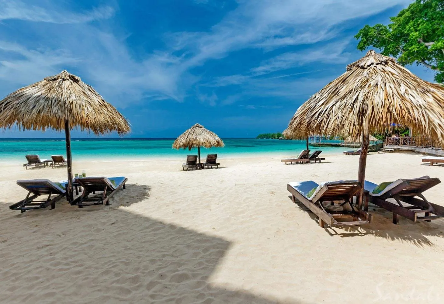 multiple lounge chairs under umbrellas on the beach