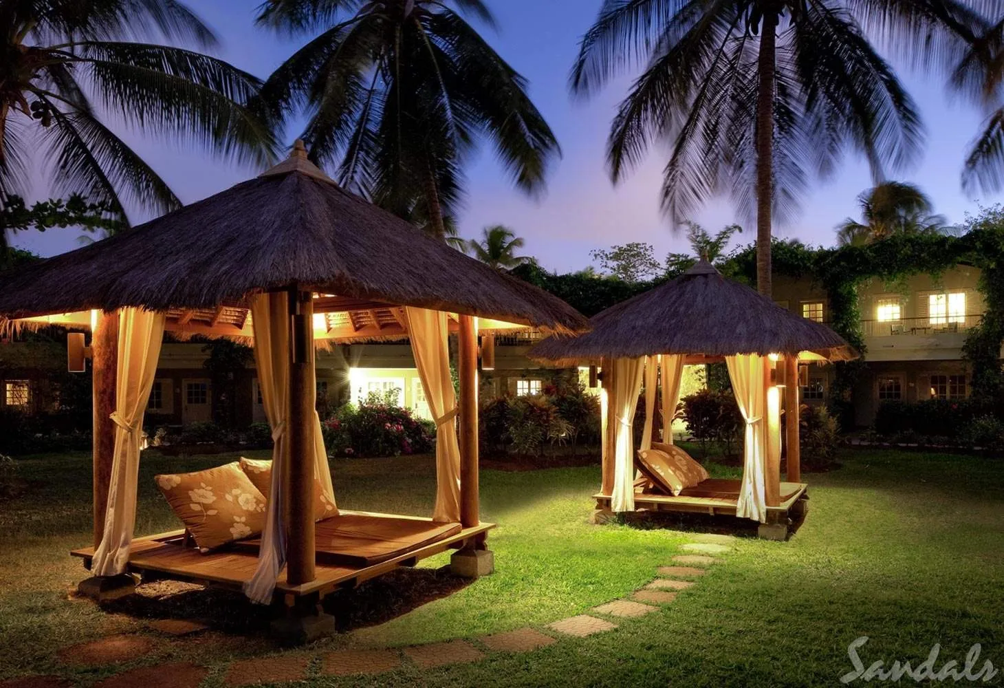 two cabanas at night with palm trees