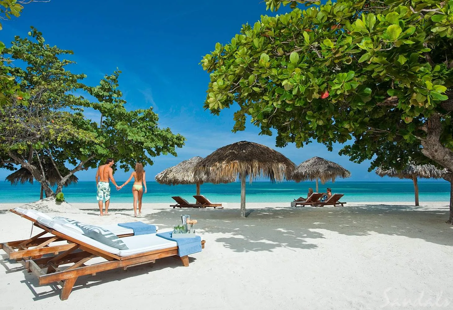 couple walking away from lounge chairs on beach