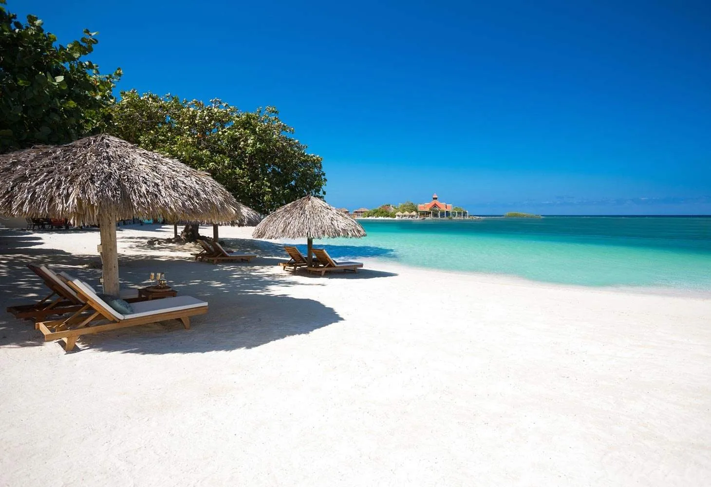 white sand beach with lounge chairs