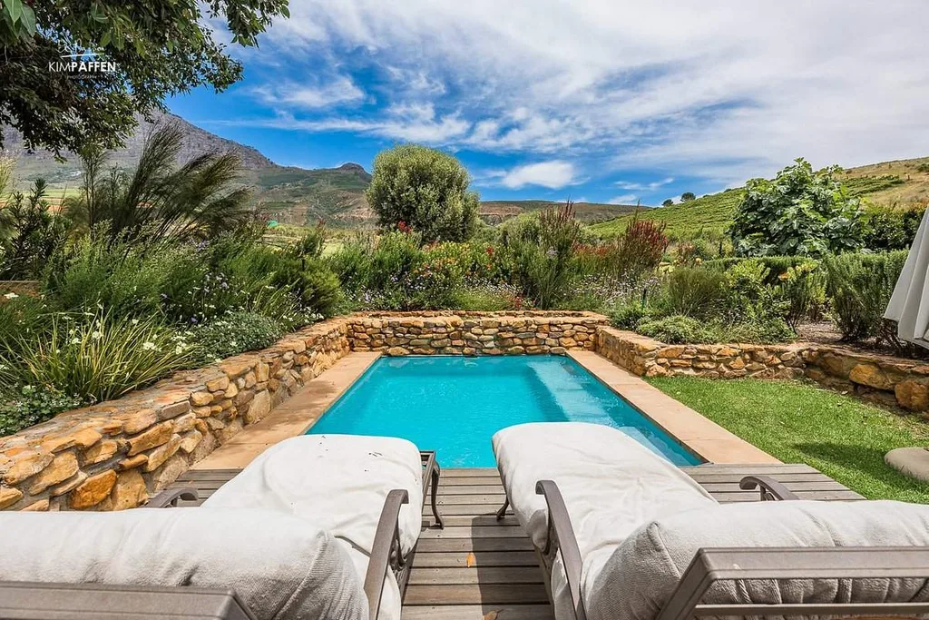two lounge chairs in front of pool with mountains in the background