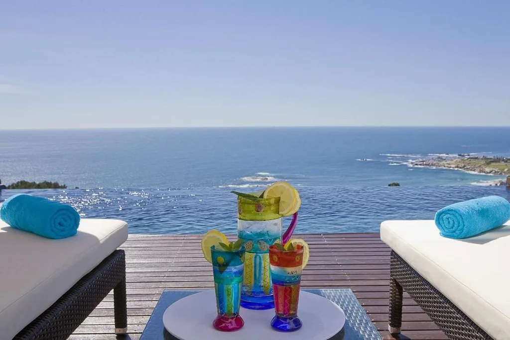 umbrella drink on table between two chairs in front of ocean