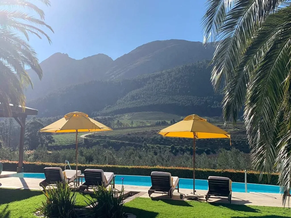 two yellow umbrellas over 4 lounge chairs with mountains in background