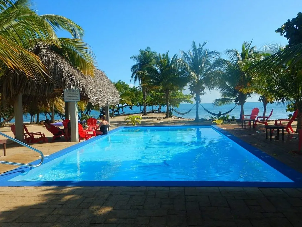 square resort pool in front of ocean with palm trees