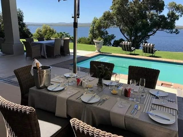 outdoor dinner table with pool behind