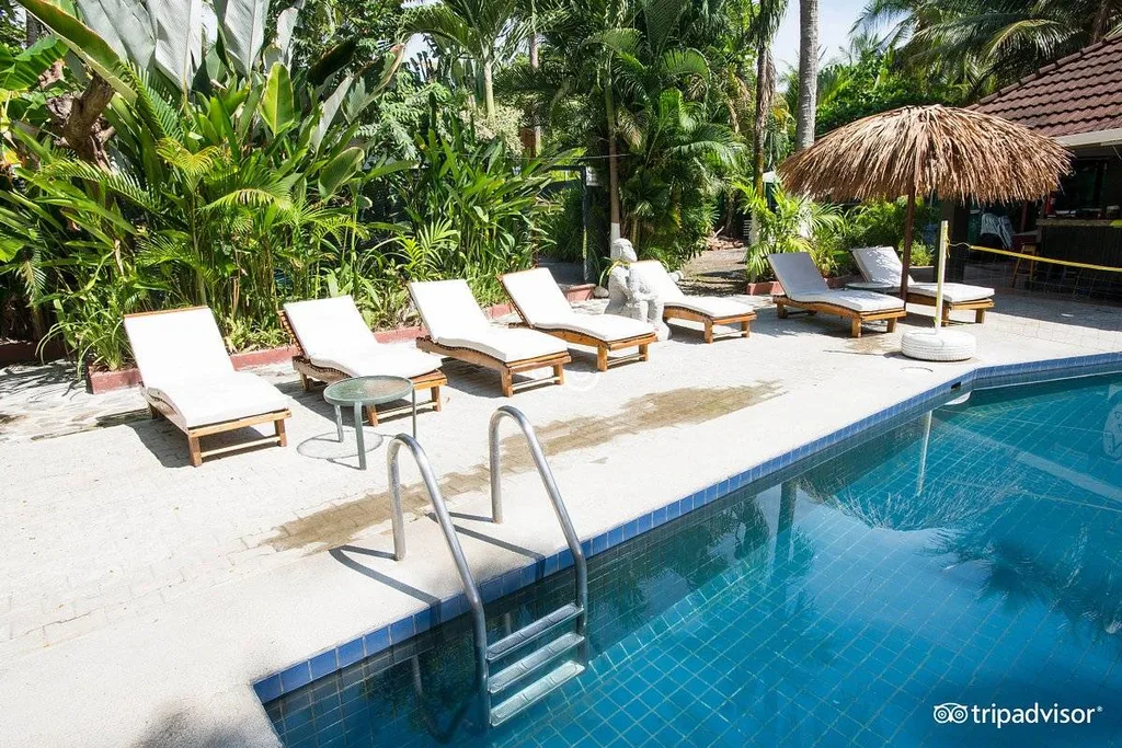 5 lounge chairs along side tropical resort pool