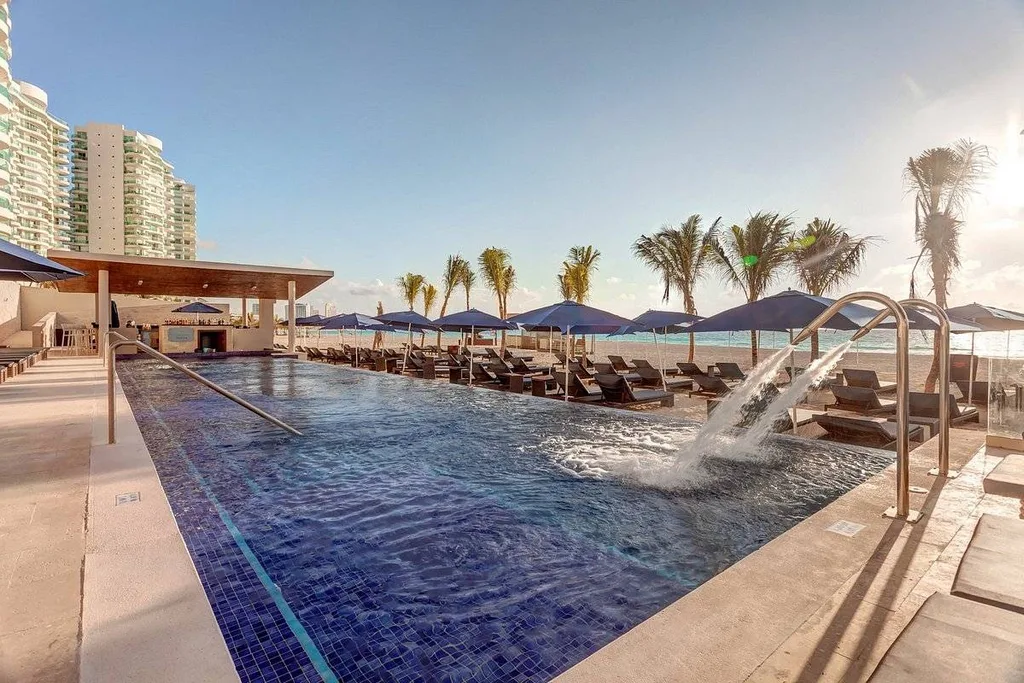 large square resort pool lined by palm trees