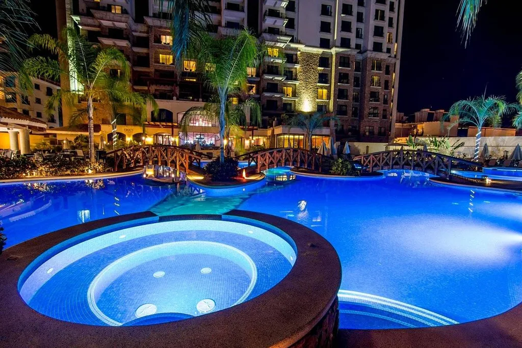resort pool with resort hot tub at night with blue light in water