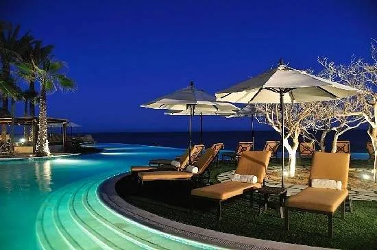 multiple lounge chairs with umbrellas at pool at night