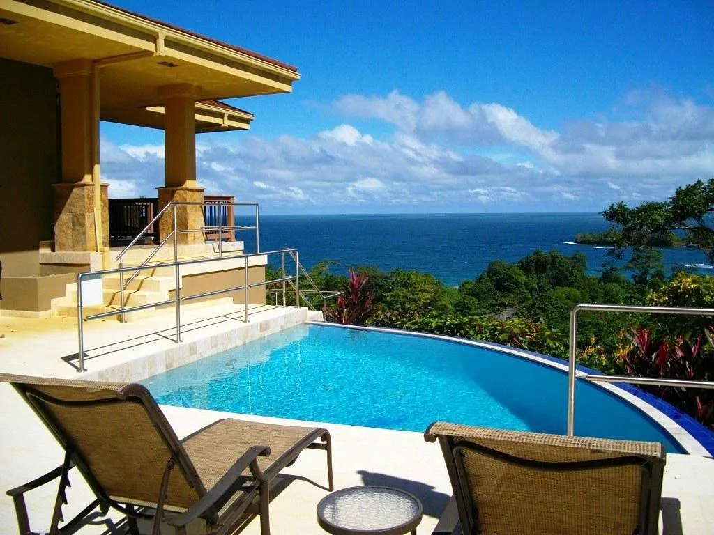 two chairs behind small pool overlooking ocean