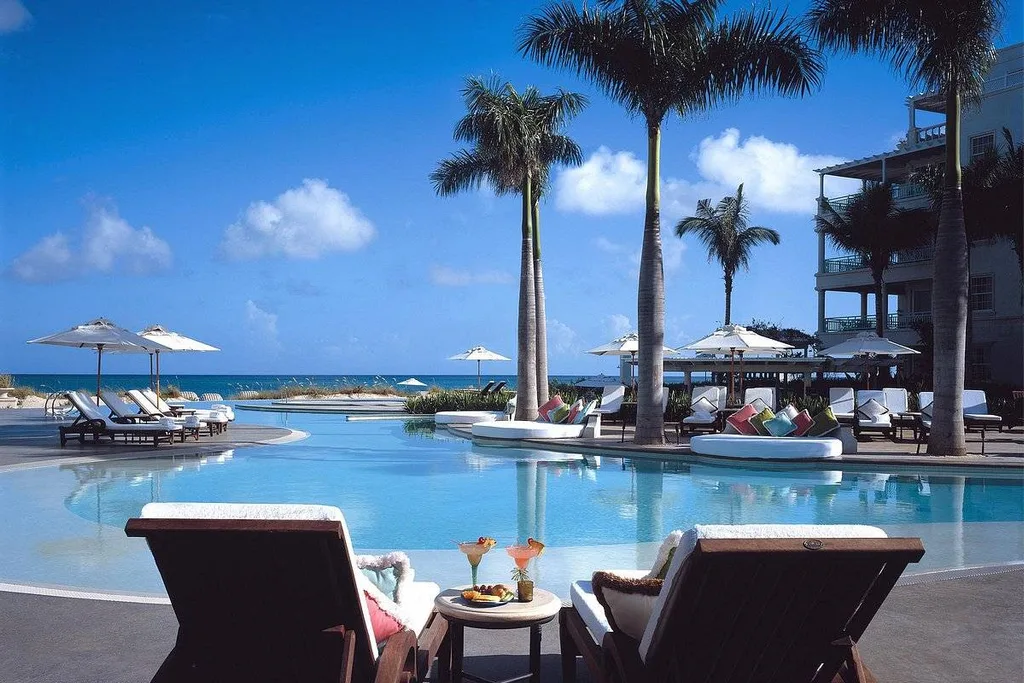 palm trees and lounge chairs around tropical pool