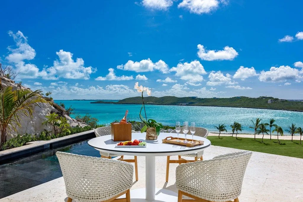 two white chairs around table with ocean in background