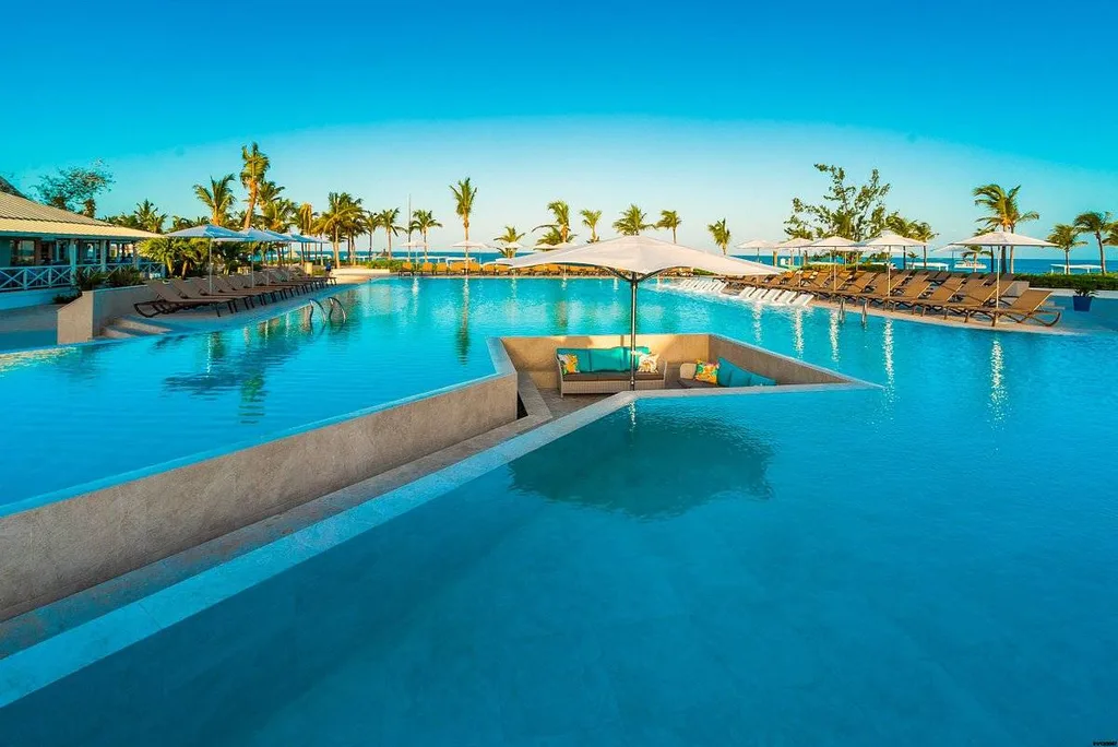 huge tropical resort pool with trench housing lounge chairs
