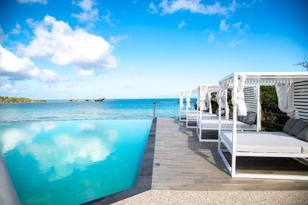 pool in front of ocean lined with cabanas