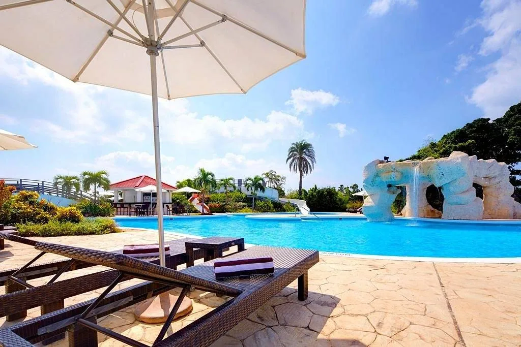 resort pool surrounded with wooden lawn chairs and umbrella