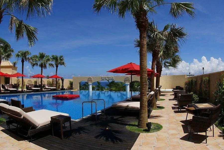 long resort pool lined with white lounge chairs and red umbrellas