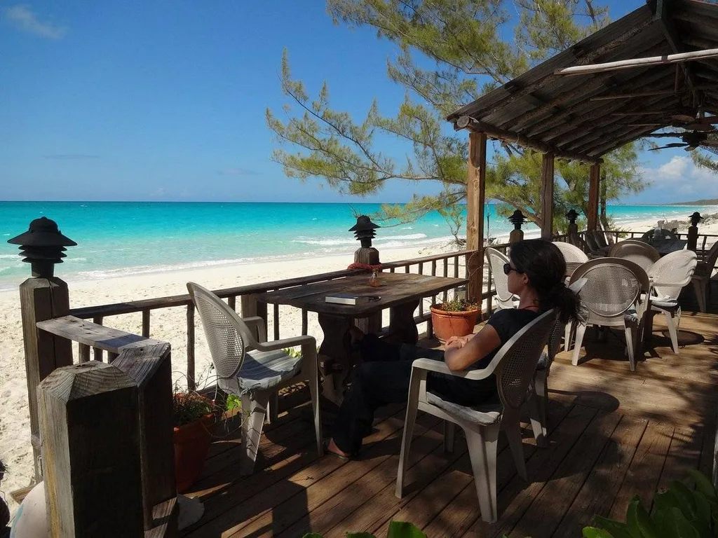 woman sitting at table on deck looking at beach
