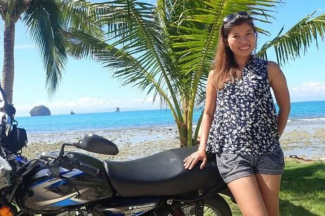 palm tree behind woman leaning on motorcycle
