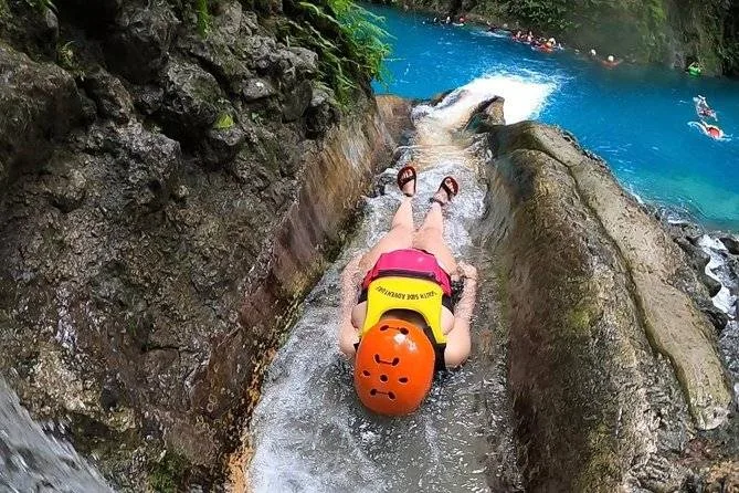 woman sliding down cliff into water