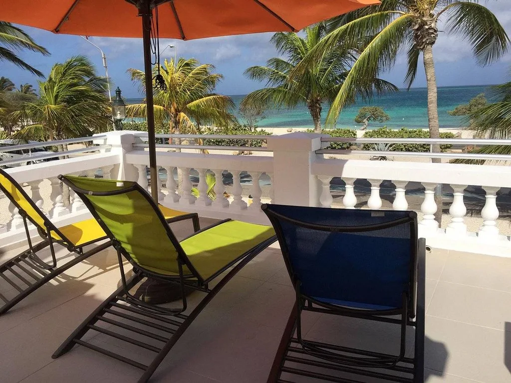 2 green lounge chairs under orange umbrella