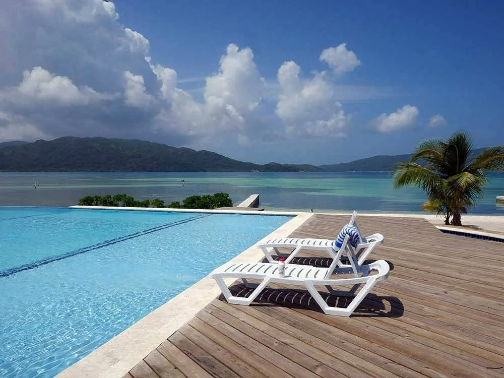 two lounge chairs by the pool with mountains in the background
