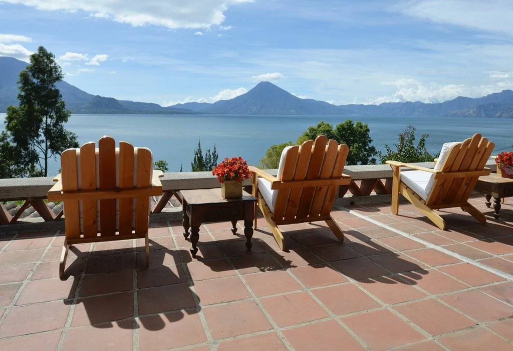 3 wooden chairs looking at mountains beyond water