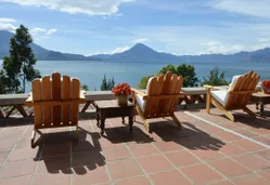 wooden chairs on wood deck looking at mountain across lake