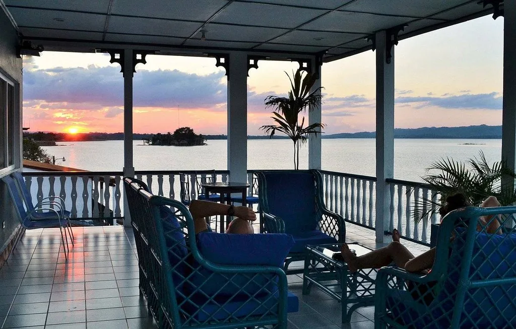 covered porch with tables and chairs on the water at sunset
