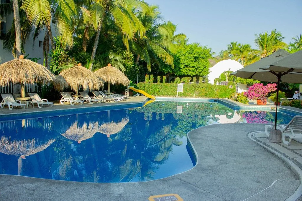 tropical resort pool with thatched umbrellas