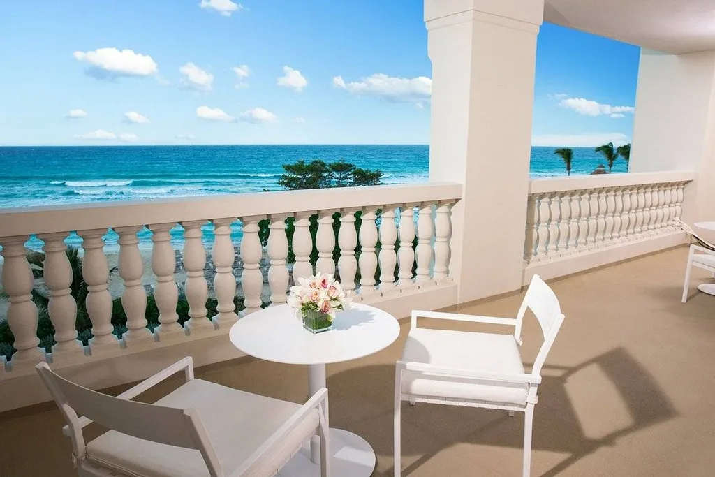 two white chairs with table on balcony overlooking ocean