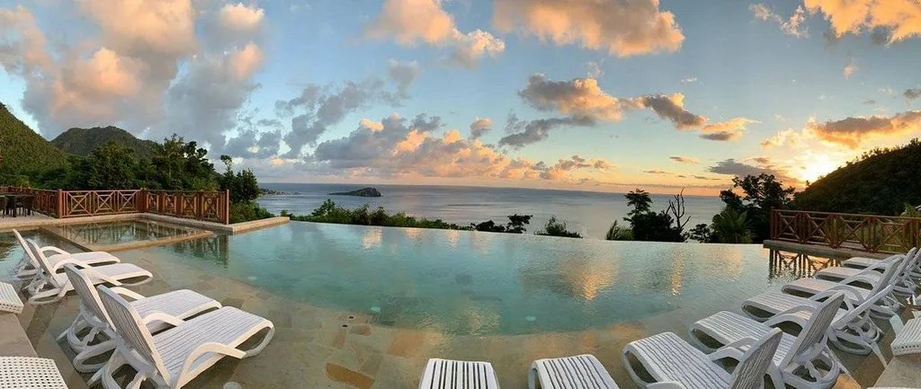 white lounge chairs around infinity pool at sunset