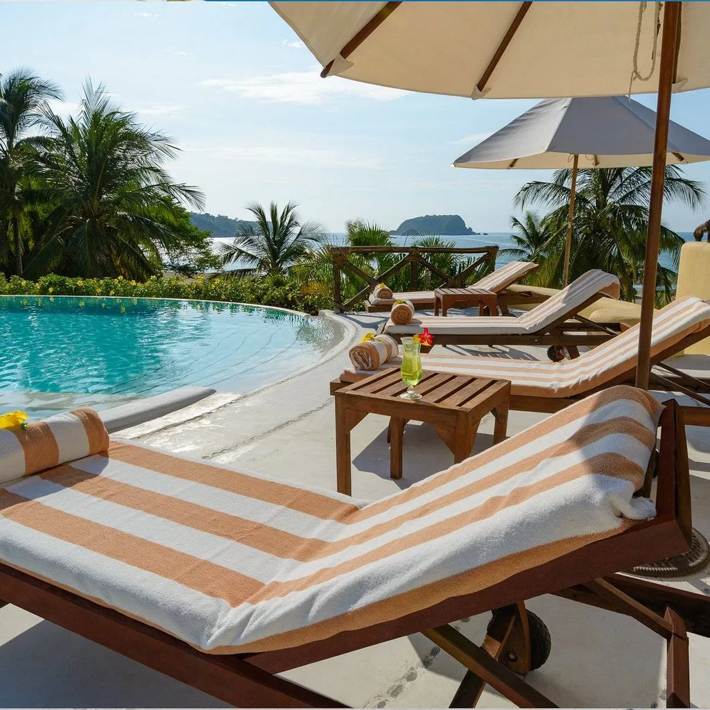 stripped lounge chairs at pool with umbrellas