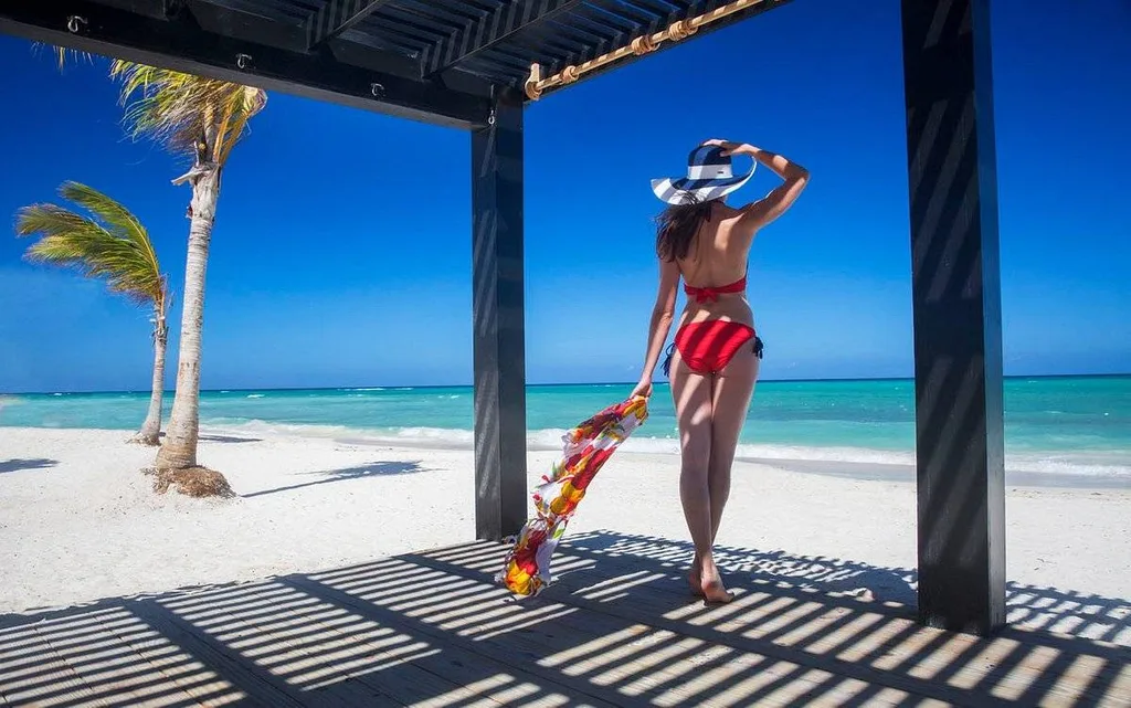 woman in red bikini under portico on beach