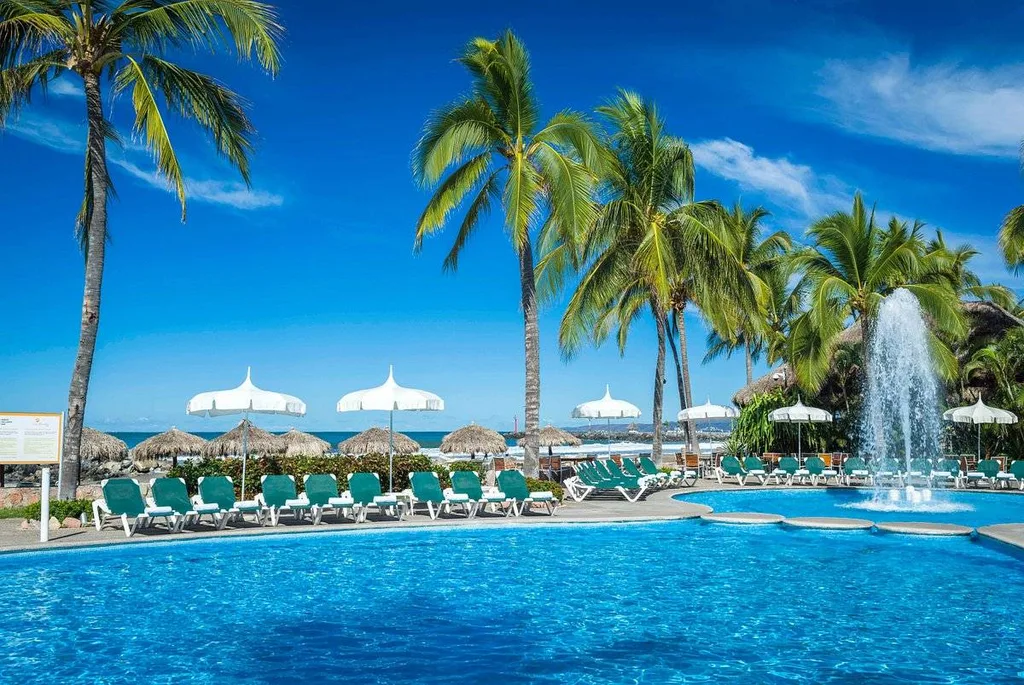 fountain in tropical resort pool with lounge chairs and umbrellas