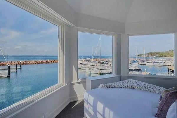 bed with 3 windows looking out onto ocean
