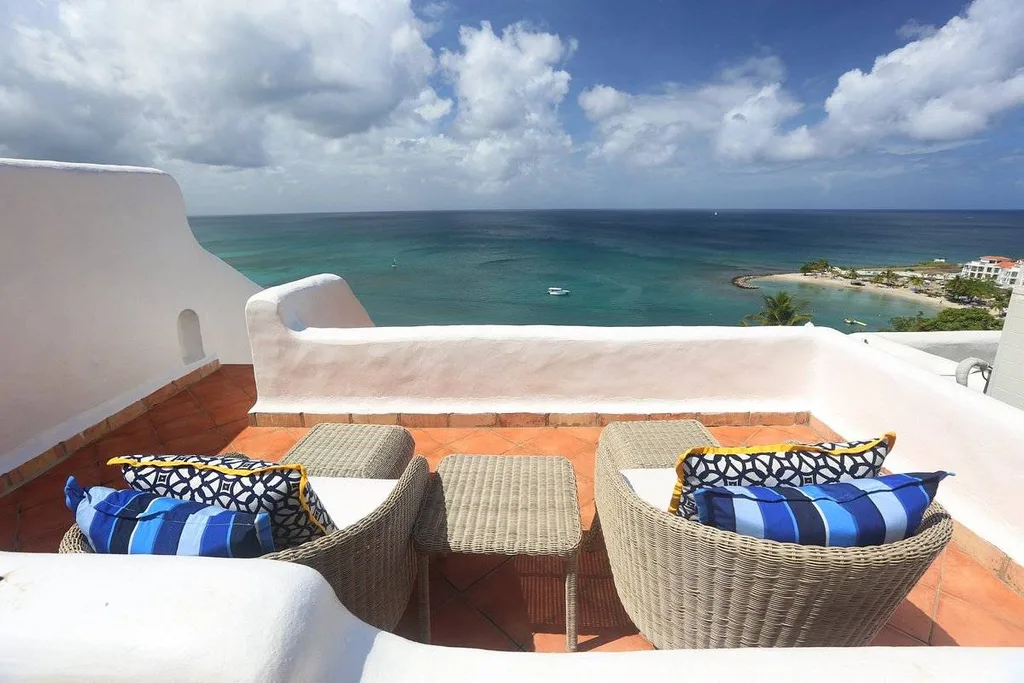 two lounge beds with blue pillows on patio at the ocean