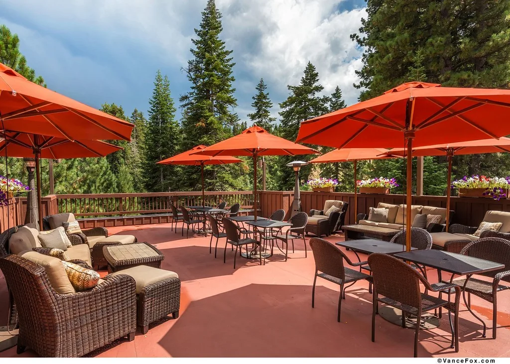 three large orange umbrellas with lounge chairs on patio in mountains