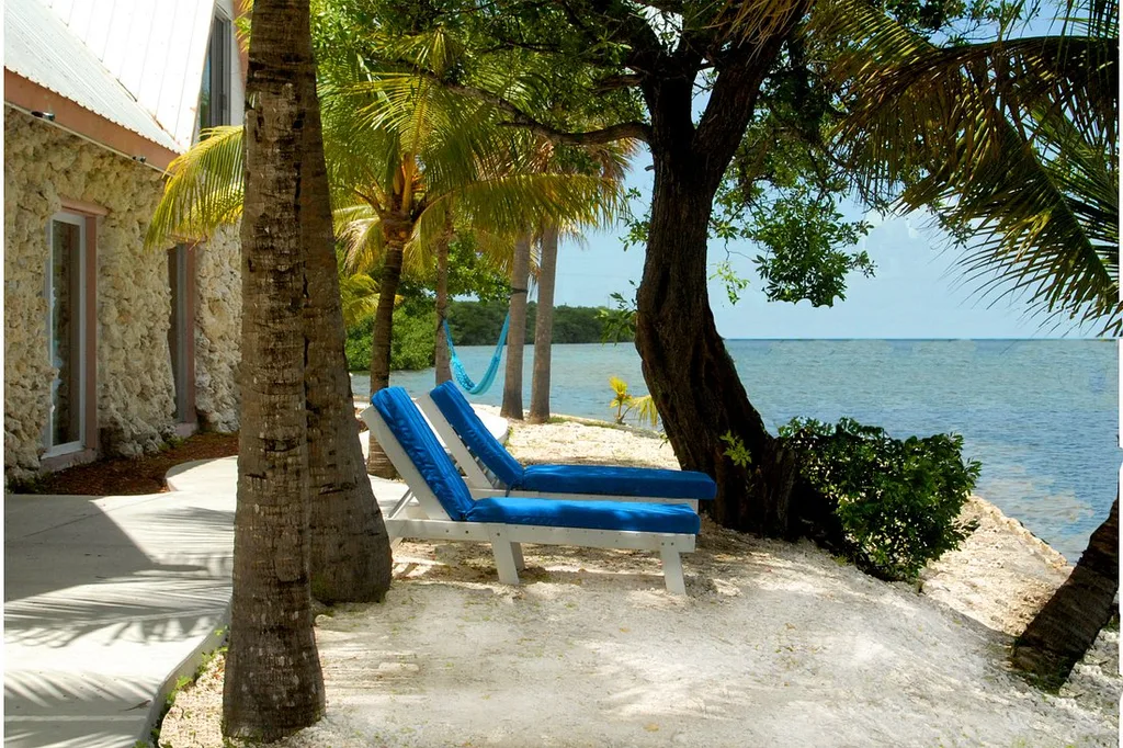 Ibis Bay Beach Resort two blue lounge chairs under trees on beach