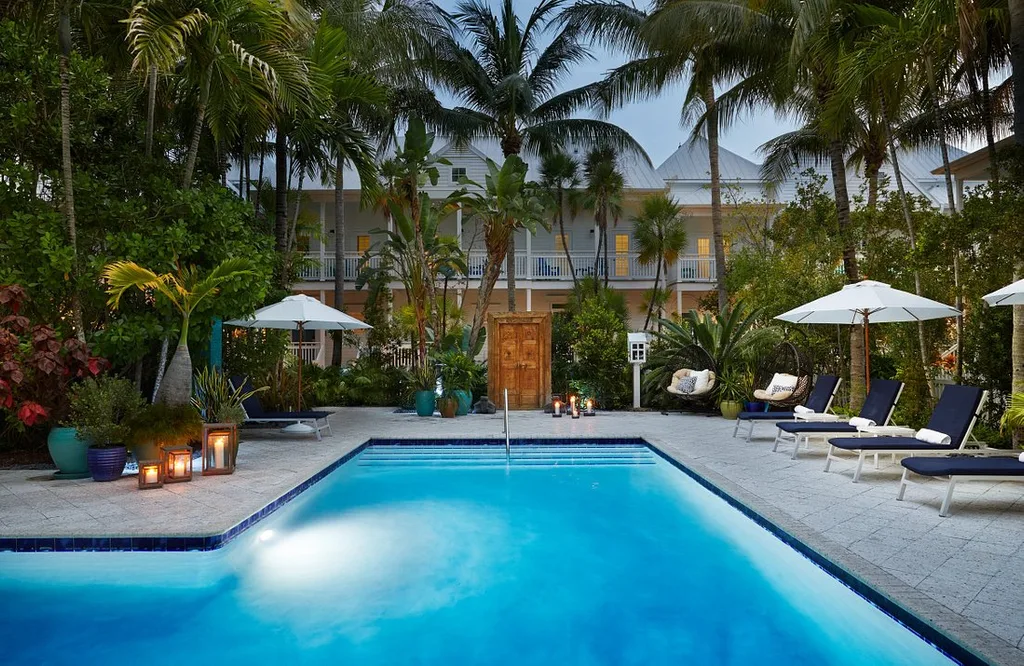 Parrot Key Hotel & Villas with lighted pool, palm trees and lounge chairs
