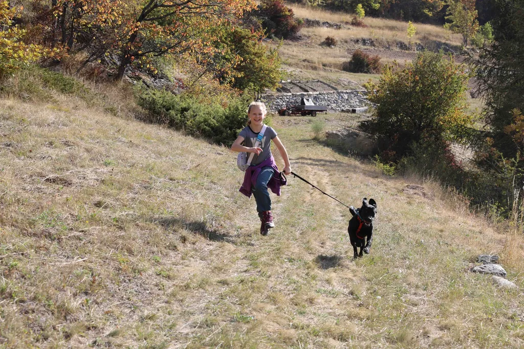 ein junges Mädchen läuft mit ihrem Hund auf einem Wanderweg