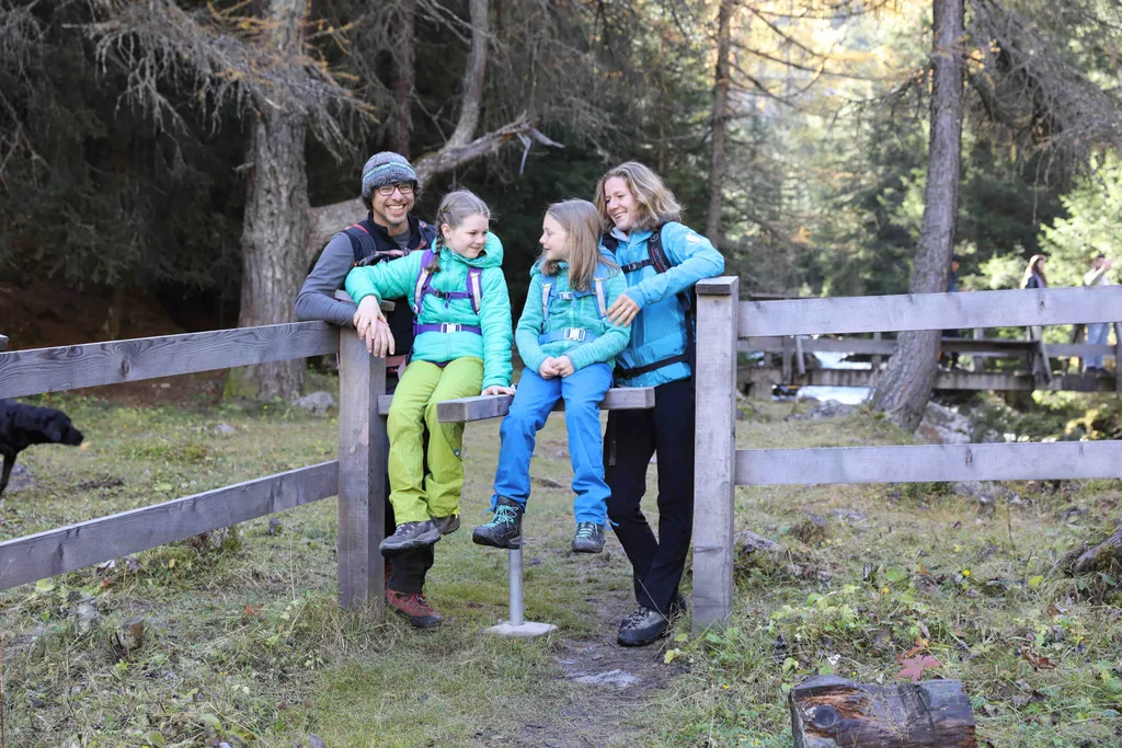 Vierköpfige Familie sitzt auf einem Zaun im Wald