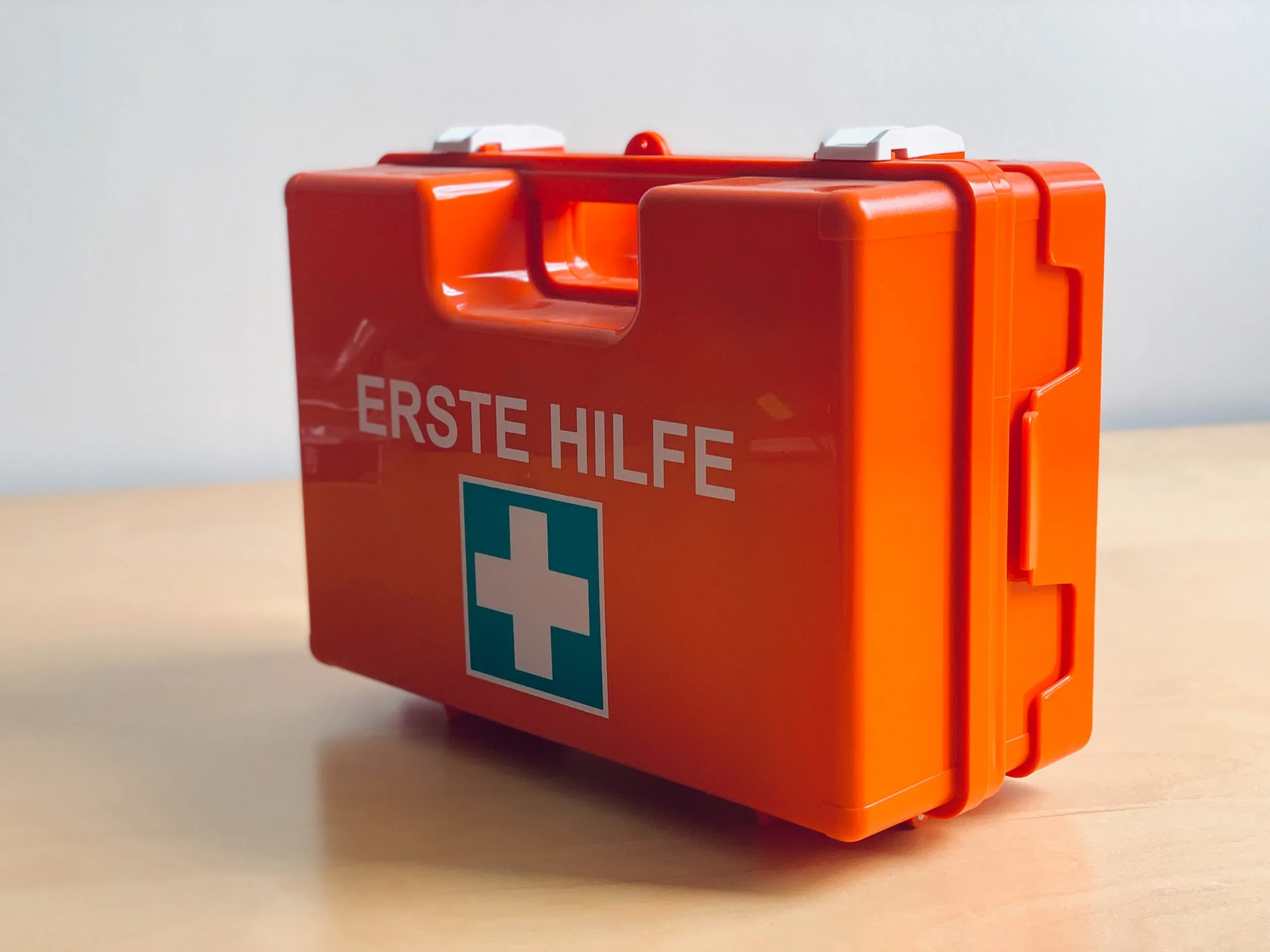 eine kleine orangefarbene Notfalldose mit einem weißen Kreuz darauf