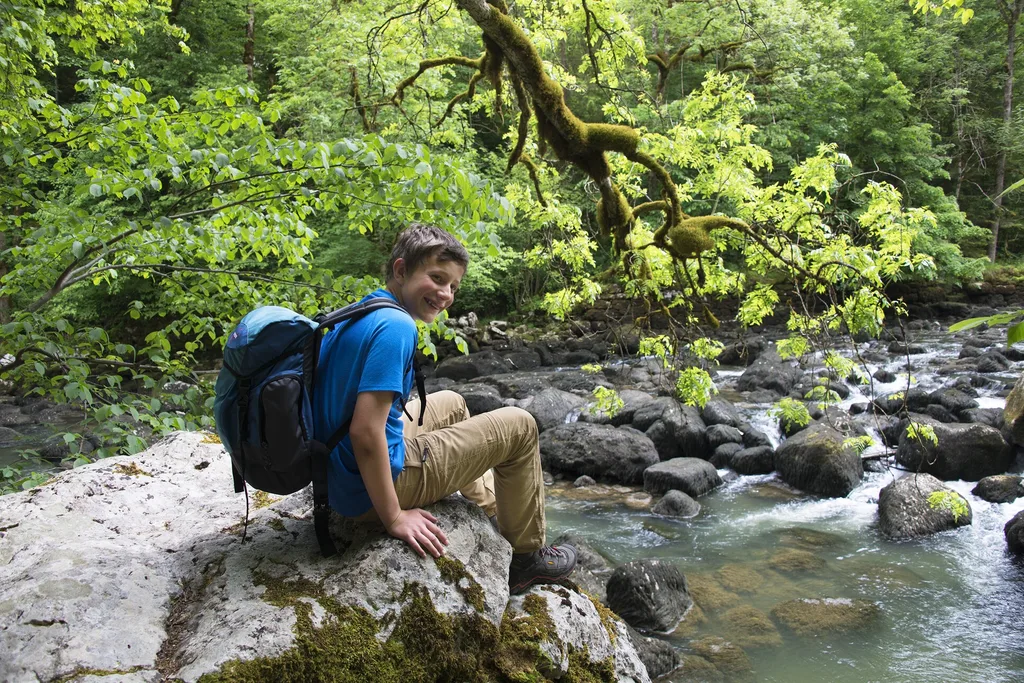 ein junger Mann sitzt auf einem Felsen am Fluss