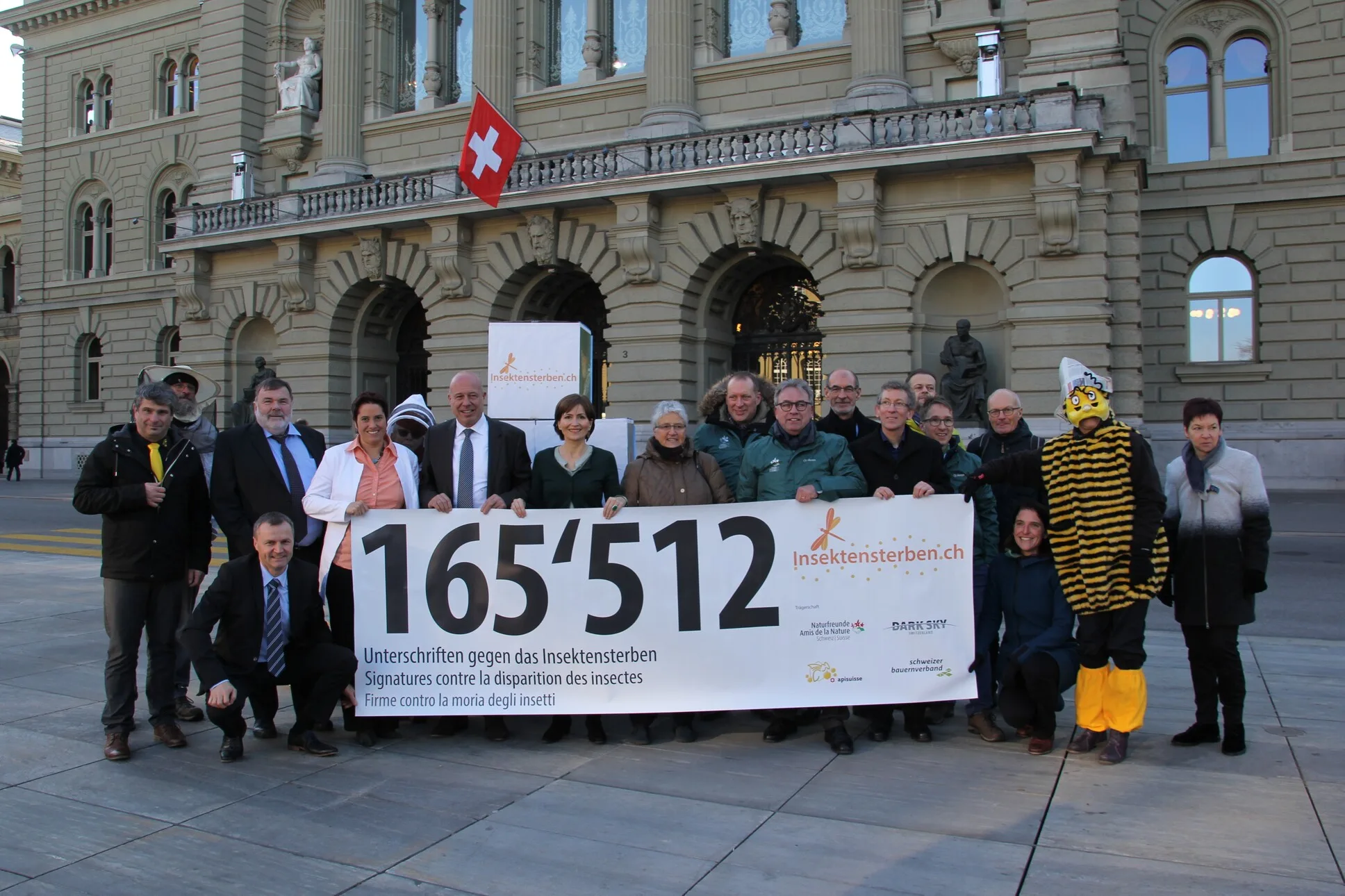 eine Gruppe von Menschen, die vor einem Gebäude stehen und ein Transparent mit der Aufschrift "1512" halten