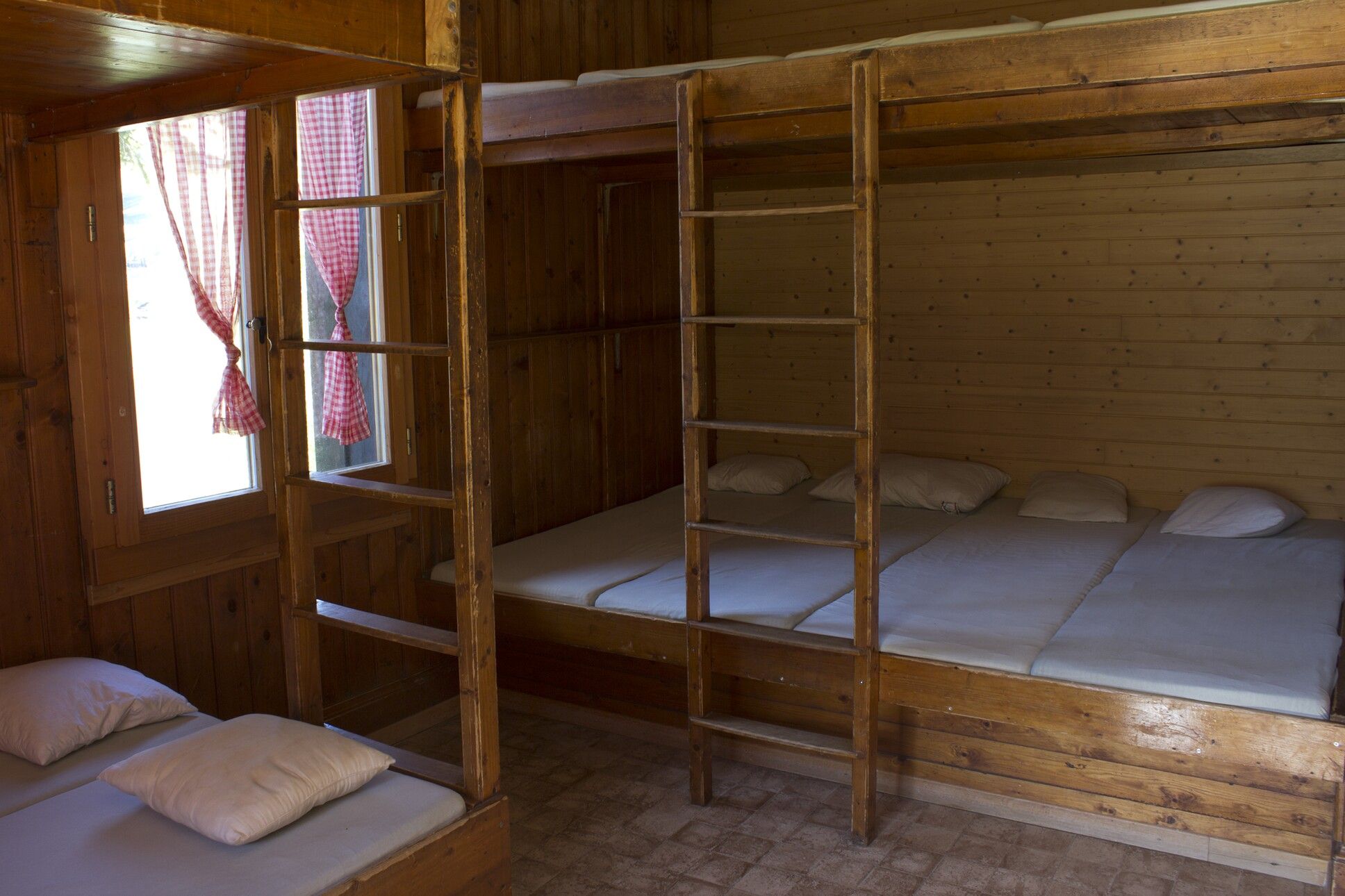ein Etagenbett aus Holz mit weißen Laken und einer Leiter 